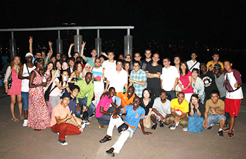 Group photo of students gathering in a sports field at night.