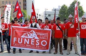 手持FUNESO的旗子與尼泊爾國旗的學生合照。學生們穿著統一的紅色T恤。