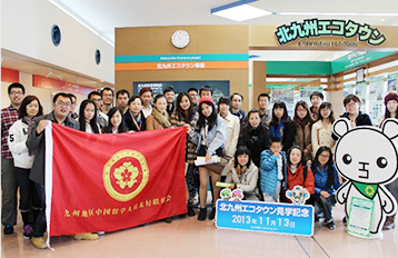 Group photo of students taken at the Kita-Kyushu EcoTown. Some of the students in front are holding a big banner with the name of their association.