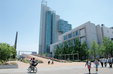 北九州市立大学の建物を背景に、学生たちが敷地内を行き来している様子